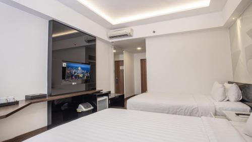 a hotel room with two beds and a flat screen tv at Golden Tulip Essential Makassar in Makassar