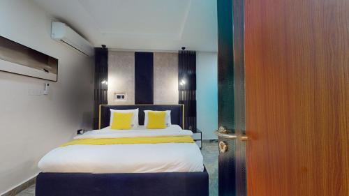 a bedroom with a bed with two yellow pillows at YANNA APARTMENT BY KHALIQUES in Abuja