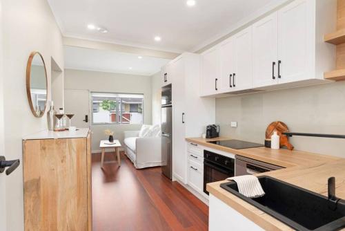 a kitchen with white cabinets and a counter top at The Elements l Air l 4 Stunning Apartments each with Private Outdoor Dining l Walk to the Beach l Pet Family and Event Friendly l Wifi l Netflix l Outdoor Shower l Communal BBQ Pavilion and Lawn Area l in Christies Beach