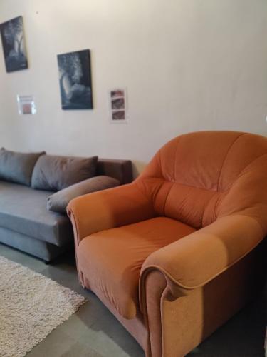 an orange chair in a living room with a couch at Find yourself apartment Dunkerque in Coudekerque-Branche