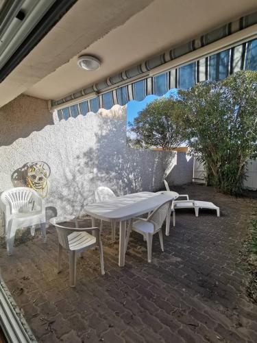 d'une terrasse avec une table, des chaises et un mur. dans l'établissement 003 Sun Village 87 Cap d'Adge, au Cap d'Agde