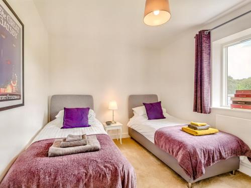 two beds in a bedroom with purple pillows at 3 Bed in Hay on Wye 77381 in Hay-on-Wye