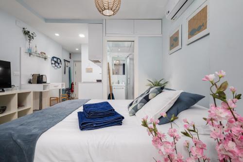 sypialnia z białym łóżkiem i niebieskimi ręcznikami w obiekcie Beach House Apartment, Playa Malagueta w Maladze