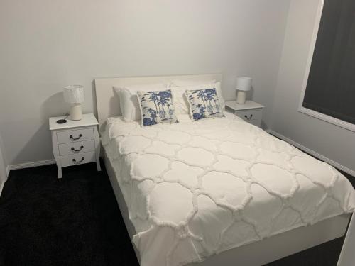 1 dormitorio con 1 cama blanca con 2 mesitas de noche y 2 lámparas en Yarrawonga Cottage en Mudgee