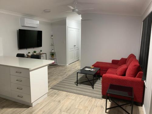 a living room with a red couch and a kitchen at Yarrawonga Cottage in Mudgee