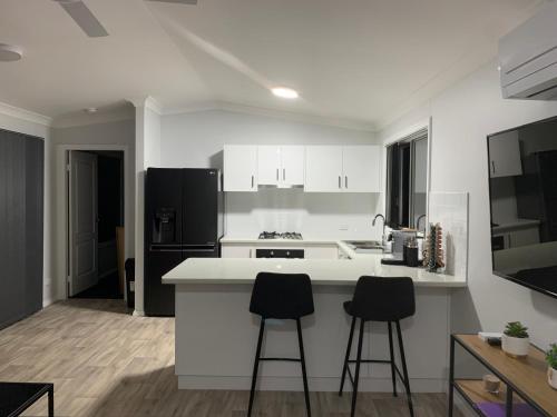 a kitchen with white cabinets and two bar stools at Yarrawonga Cottage in Mudgee