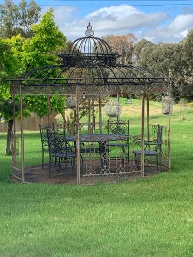 a gazebo with a table and chairs in the grass at Yarrawonga Cottage in Mudgee