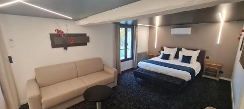 a hotel room with a bed and a couch at Le Sainte Jeanne in Cormeilles-en-Vexin