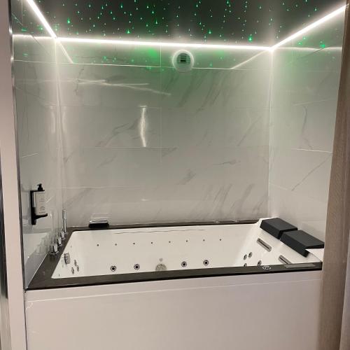 a bathroom with a bath tub with green lights at Le Sainte Jeanne in Cormeilles-en-Vexin