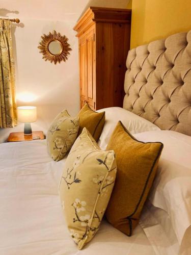 a bedroom with a bed with pillows and a mirror at Wells Cottage in Malvern Wells