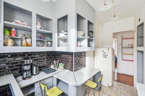 une cuisine avec des placards blancs, une table et des chaises jaunes dans l'établissement Spacious apartement 'Canal Saint Martin' for 6 by Weekome, à Paris