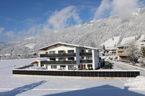 a building in the snow in front of a mountain at Kaiser Apart Walchsee in Walchsee