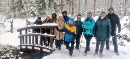 a group of people standing next to a bench in the snow at Hotel Nowy Zdrój - Centrum Zdrowia i Wypoczynku in Polanica-Zdrój