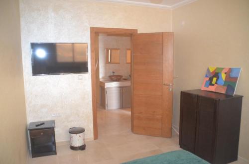 a living room with a television and a door to a bathroom at Tamrisurfcamp in Tamri