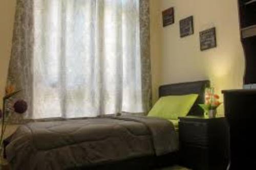 1 dormitorio con cama y ventana con cortina en Worker's Apartman-Munkásszálló, en Igricetanya