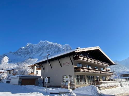 a building in the snow with a mountain in the background at Rustika - Appartements & Spa in Ehrwald