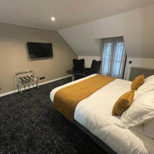 a hotel room with a bed and a flat screen tv at Le Sainte Jeanne in Cormeilles-en-Vexin