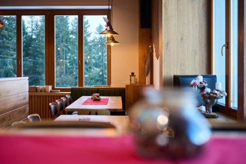 a dining room with tables and chairs and windows at Ribniška koča in Ribnica na Pohorju