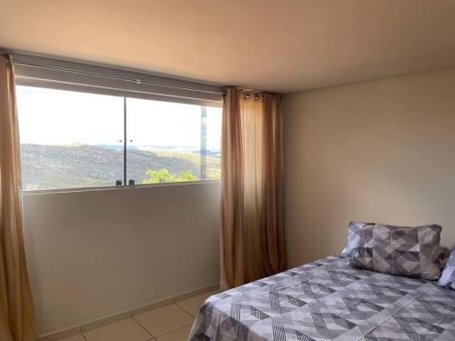 sypialnia z łóżkiem i dużym oknem w obiekcie Residencial Vista da Serra w mieście Diamantina