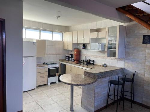una cocina con electrodomésticos blancos, mesa y sillas en Residencial Vista da Serra en Diamantina