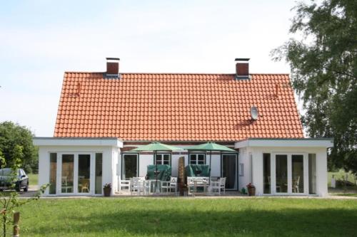 ein Haus mit einem orangenen Dach mit Stühlen und Sonnenschirmen in der Unterkunft FerienGut Gaarz - Cottage 29 in Göhl