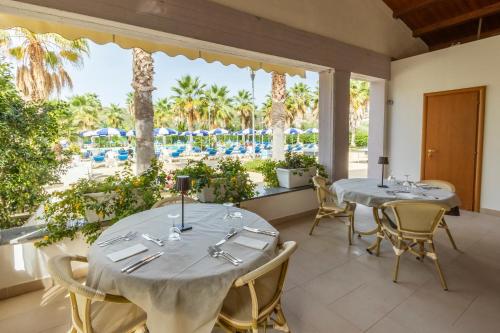 2 Tische in einem Zimmer mit Poolblick in der Unterkunft Prince Franklyn Hotel in Santa Maria di Castellabate