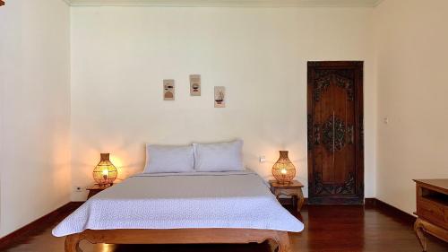 a bedroom with a large bed with two lamps at Alizee Villa in Seminyak