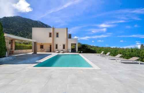 a villa with a swimming pool in front of a house at Vlasis' Eden Villa in Sálakos