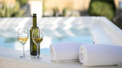 a bottle of wine and two glasses on a table at Aeolos Villas Sustainable Living in Agkidia