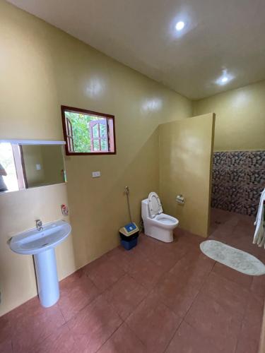 baño con lavabo y aseo y ventana en Tauig Beach Resort, en Moalboal