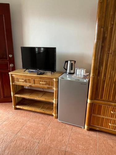 Tauig Beach Resort في موالبوال: تلفزيون وثلاجة صغيرة في الغرفة