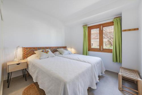 Duas camas num quarto branco com uma janela em Apartment Blavamar em El Port