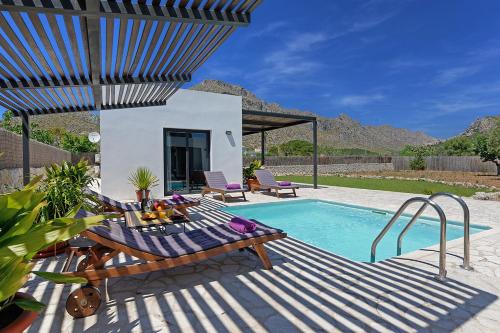 een zwembad met een tafel en stoelen naast een huis bij Villa Marcelino in Port de Pollença