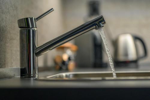 a stream of water pouring from a kitchen faucet at black well in Jablonec nad Nisou