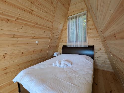 a white dog laying on a bed in a wooden room at Prime House Cottages in Keda