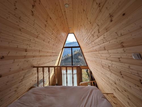 a bedroom in a log cabin with a window at Prime House Cottages in Keda