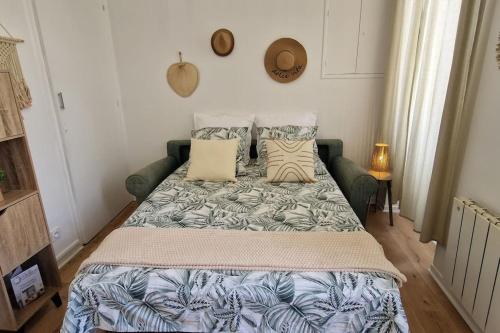 Schlafzimmer mit einem Bett mit einer blauen und weißen Bettdecke in der Unterkunft Le Cocon Margalais in Margaux