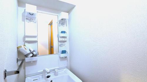 a white bathroom with a sink and a mirror at KIYAZA Space Sapporo in Sapporo