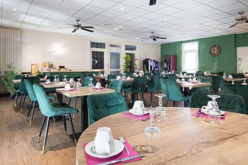 a dining room with tables and green chairs at Logis Hôtel Restaurant L'Abri in Le Puy en Velay