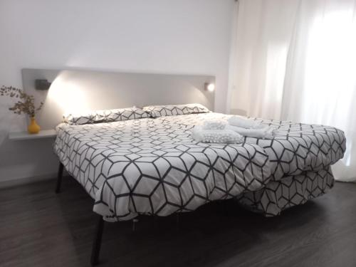 1 dormitorio con 1 cama con edredón blanco y negro en Apartamentos céntricos a 10 min de la playa, en Almería