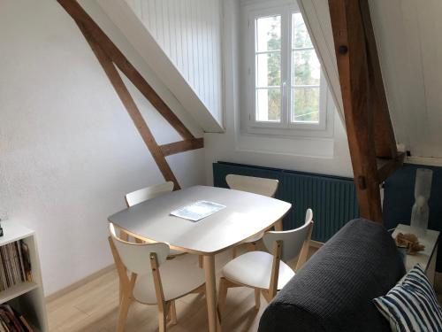 einen Tisch und Stühle in einem Zimmer mit Fenster in der Unterkunft Numéro 7 in Le Tronquay