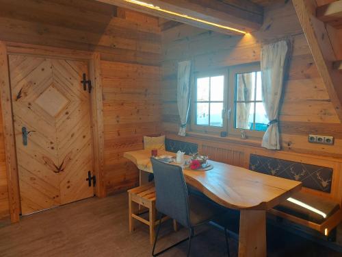 a dining room with a wooden table and a window at Chalet Troadkasten Biohof Kreilgut in Walchegg