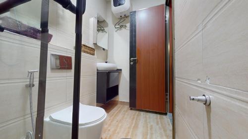 a bathroom with a toilet and a wooden door at YANNA APARTMENT BY KHALIQUES in Abuja