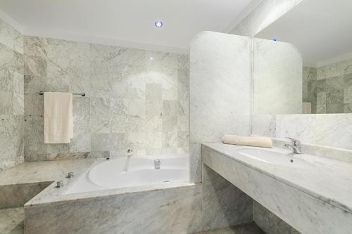 a white bathroom with a tub and a sink at Apartment Vistamar IV in Port de Pollensa