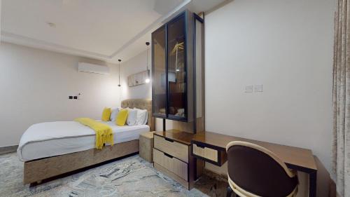 a bedroom with a bed and a desk and a chair at YANNA APARTMENT BY KHALIQUES in Abuja