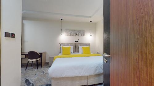 a bedroom with a bed with yellow pillows and a desk at YANNA APARTMENT BY KHALIQUES in Abuja