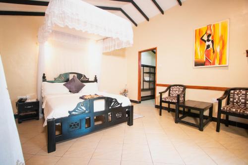 ein Schlafzimmer mit einem Bett und zwei Stühlen darin in der Unterkunft Kijiji Beach Resort in Daressalam
