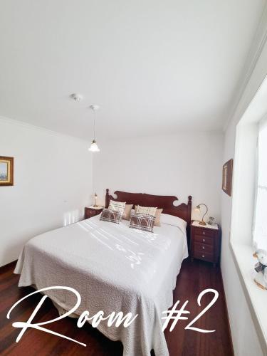 a white bedroom with a bed with a sign that reads room at Casa da Ladeira in Fajã da Ovelha