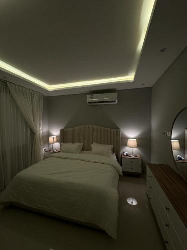 a bedroom with a white bed with two lamps at شقة فاخرة (مدخل خاص - دخول ذاتي) in Riyadh
