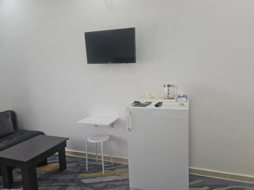 a living room with a tv on a white wall at فندق الشموخ Hotel Al Shmokh in Bir Gandouz